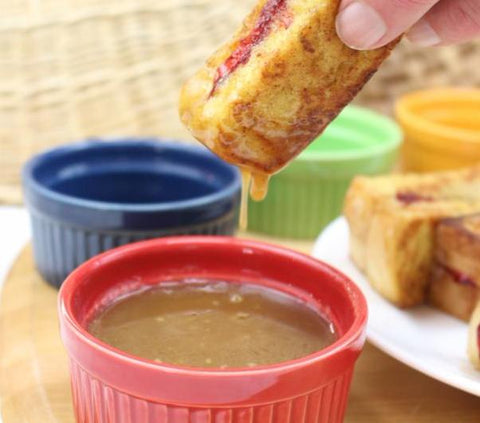Dipping French toast sticks made with a bread machine mix in buttermilk syrup mix